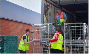 FareShare workers in safety vests load metal cages onto a truck at a loading dock. Photo credit: FareShare Thames Valley/SOFEA